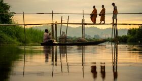 Buddhist Monks walking on the wooden bridge, Thailand